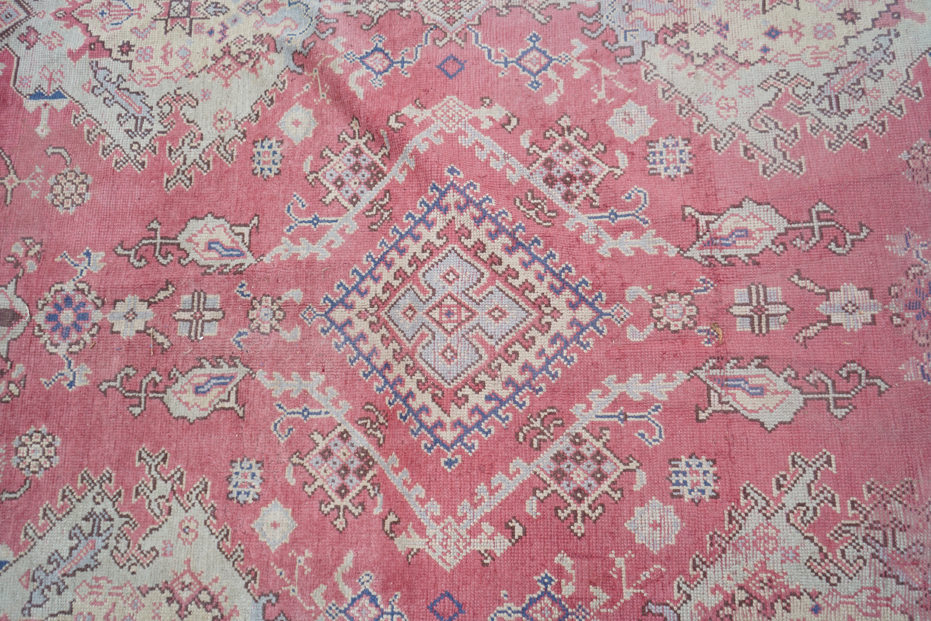 A large Turkish faded red ground carpet